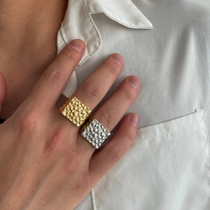 Men's square signet ring with gold and silver hammered texture on white shirt background