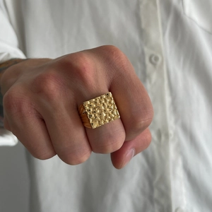 Close-up of a men's gold square nugget texture ring worn on a hand with a white shirt
