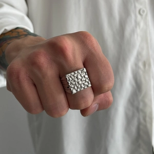 Macro detail of men's silver square ring with hammered metal texture and punk style