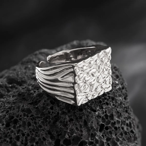 Macro shot of silver textured square ring face on volcanic rock background