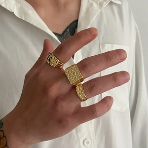 Détail de bagues dorées pour homme avec texture lave portées à la main style hip-hop rétro