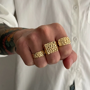 Gros plan de bagues dorées pour hommes avec texture nugget sur main et chemise blanche