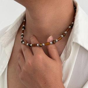 Men's necklace with tiger eye beads and silver spacers on white shirt background