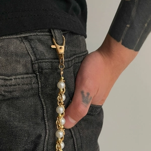 Hip-hop style gold metal chain with white pearls and lobster clasp on grey denim pants
