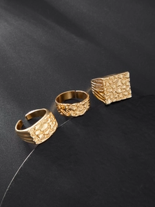 Vue détaillée de trois bagues dorées à texture pépite sur un socle de présentation