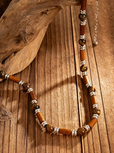 Detail of wooden beads and tiger eye stones on vintage ethnic style necklace for men