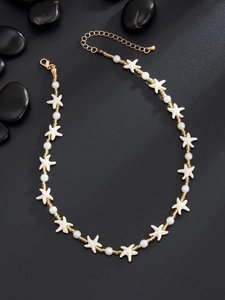 Détail du collier étoile de mer avec perles d'imitation sur un fond texturé noir