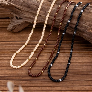 Detail of handcrafted beaded necklaces in beige, brown and black on weathered wood