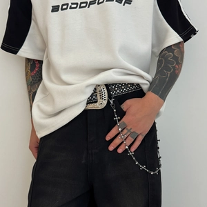 Detail of silver cross pant chain with rhinestones and lobster clasp on black trousers