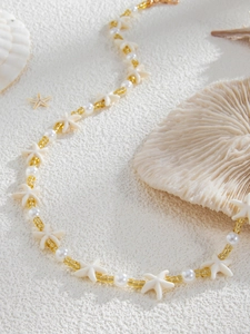 Vue détaillée d'un collier de perles avec étoile de mer et perles nacrées sur sable blanc
