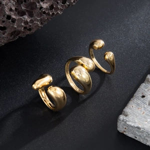 Dreiteiliges goldenes Ring-Set mit flüssigem Metall-Design auf dunklem Steinhintergrund