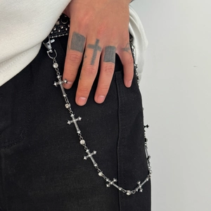 Detail of silver cross pant chain with crystals hanging on black denim jeans