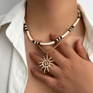 Bohemian layered necklace with wooden beads and sun pendant on white shirt background