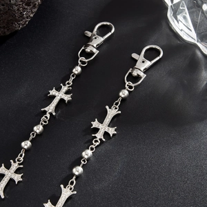 Dettaglio di ciondoli a croce gotica argentati con strass scintillanti e chiusure a moschettone