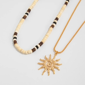 Detail of wooden bead strand and gold sun pendant necklace with hammered texture