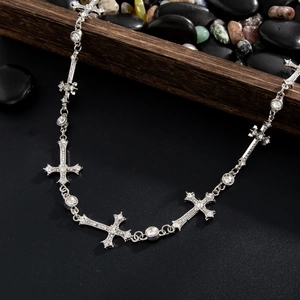 Detail of silver cross pant chain with crystal studs and rhinestones on black background