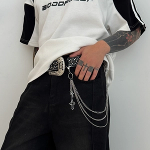 Detail of multilayer cross pendants and punk style studded leather belt on pants