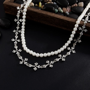 Détail du collier argenté à deux rangs avec perles nacrées et motifs de croix évidées