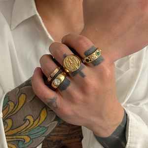 Men's hip hop gold ring set featuring engraved signets and green gemstone on tattooed hand