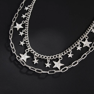 Detail of silver multi-layer pant chain with star charms on textured black background