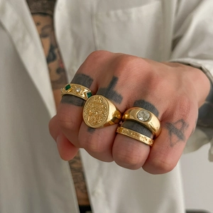Detail of four gold vintage rings featuring emerald stone, coat of arms, and cross motifs