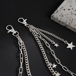 Detail of silver multi-layered pant chain with star charms and lobster clasp on black background