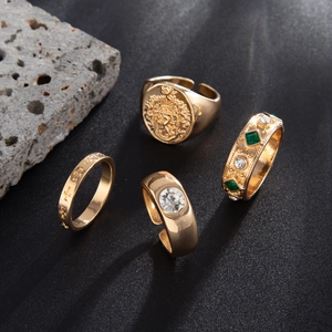 Macro view of four vintage gold rings with lion seal, cross and green gemstone accents