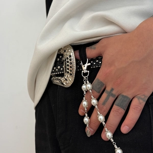Detail of pearl street style trousers chain with silver lobster clasp on black leather belt