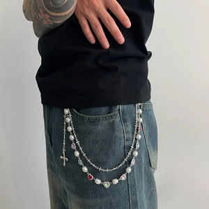 Detail of multi-layered silver pants chain with pearls, colorful crystals and cross pendant