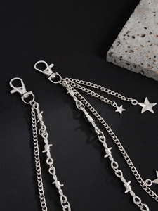 Detail of punk silver metal trousers chain featuring star charm and barbed wire link design