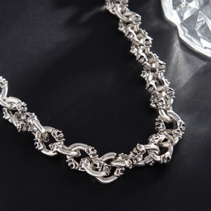 Close-up of vintage silver skull charms on interlocking metal rings gothic punk style
