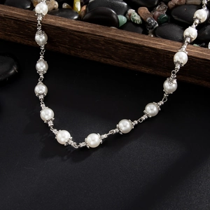 Close-up of white pearls with ornate silver metal caps and link details on a necklace