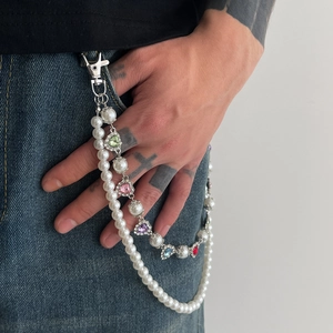 Detail of layered pearl trouser chain with colorful heart rhinestones on denim jeans