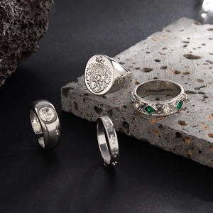 Detail shot of four vintage silver hip hop rings with lion crest and emerald green stones