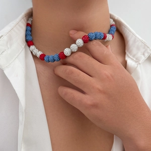 Close-up of beaded necklace with red, white, and blue rhinestones on a male model