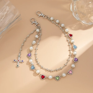 Detail of multi-layer trouser chain featuring pearls, silver crosses and colorful heart gems