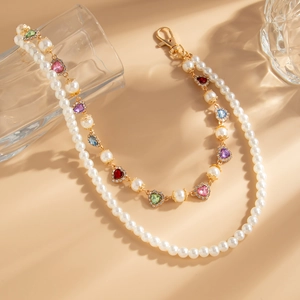 Détail d'une chaîne de pantalon double rang en perles avec cœurs colorés et fermoir doré