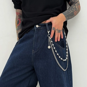 Detail of double-layered metal hip hop chain with white pearls on denim jeans