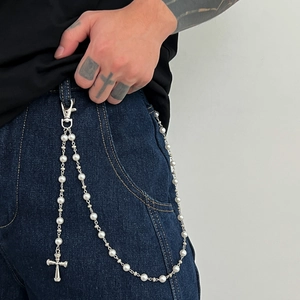 Détail d'une chaîne de pantalon en perles hip hop avec pendentif croix sur un jean