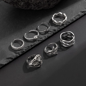 Detail of seven vintage silver-finish alloy rings with star embossing on dark rock