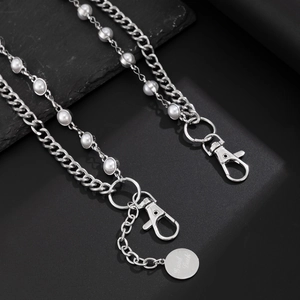 Detail of layered silver Cuban chain with pearls and 'Good Luck' engraved tag pendant