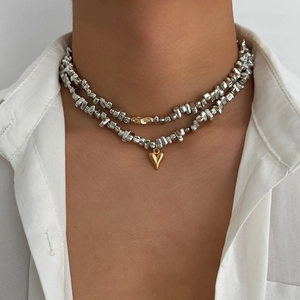 Detail of silver irregular beaded necklace set with golden heart and bean charms