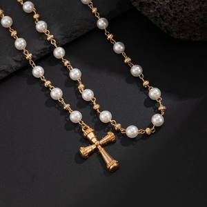 Gros plan du pendentif croix dorée avec perles sur une surface noire texturée