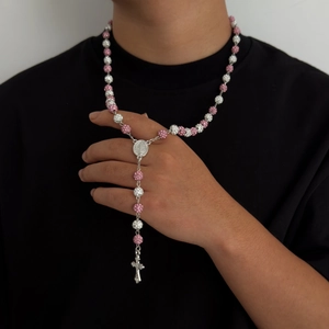 Dettaglio della collana stile rosario con perle rosa di strass e ciondolo a croce su modello