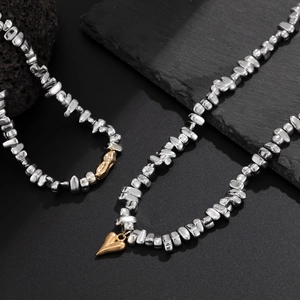 Detailed view of silver irregular beaded necklace and bracelet set with golden heart pendant