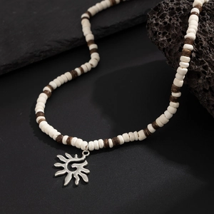 Gros plan sur collier perlé ethnique avec pendentif soleil en argent sur roche