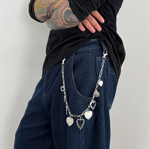 Dettaglio della catena da vita punk argento con vari pendenti a forma di cuore su jeans