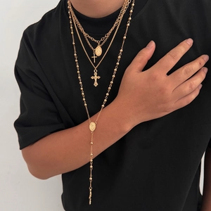 Gros plan de colliers dorés superposés avec pendentifs croix et médaille sainte