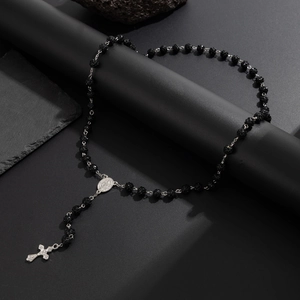 Dettaglio della collana di perle acriliche nere con crocifisso e medaglia d'argento