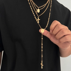 Gros plan détaillé de colliers multicouches dorés pour hommes avec croix et médailles saintes